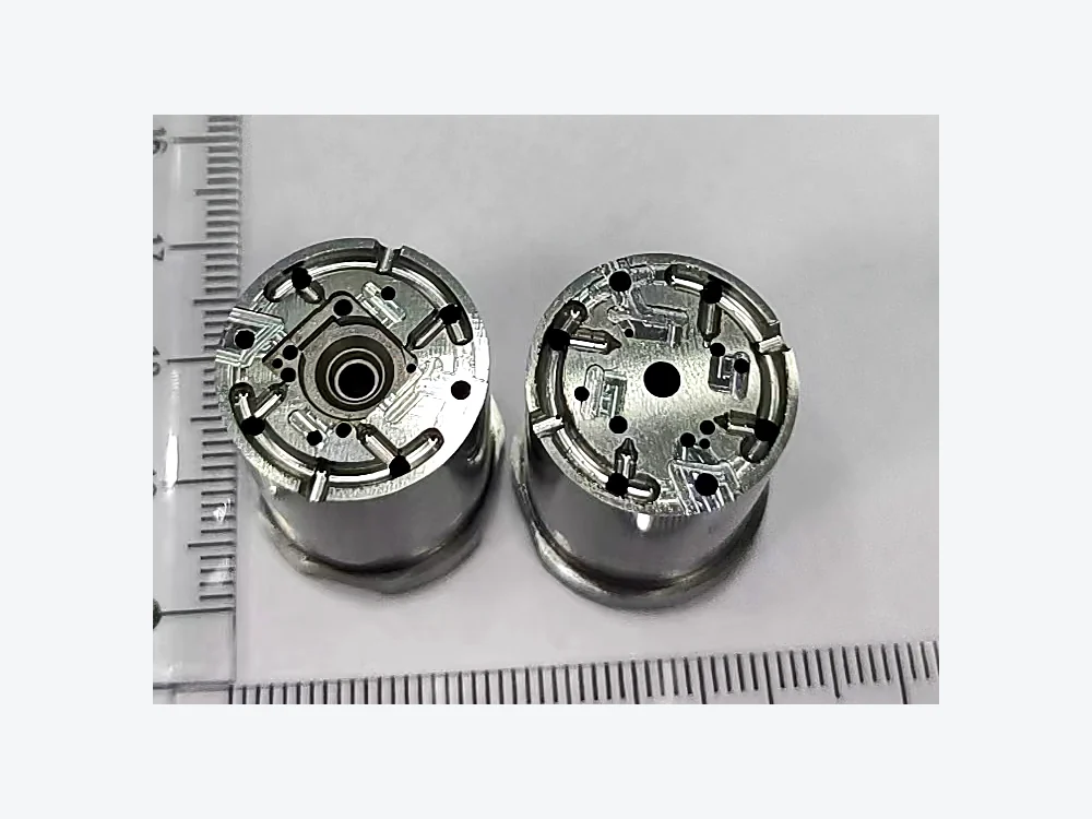 Two small cylindrical machined components shown with a reference scale